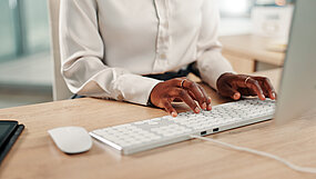 Bild på en kvinna som skriver på endator. man ser bara arnmar och händer